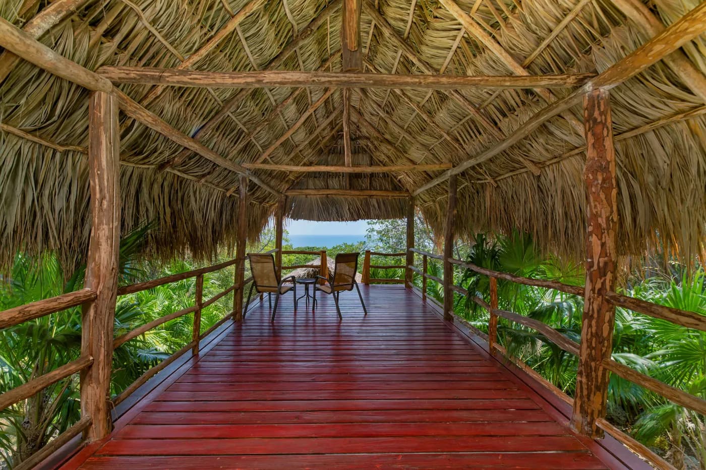 Covered wooden terrace surrounded by tropical foliage at the Saint Helene cabin